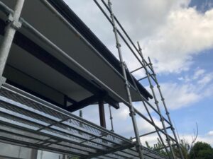 足場から見上げた軒裏と青空の塗装工事中の風景